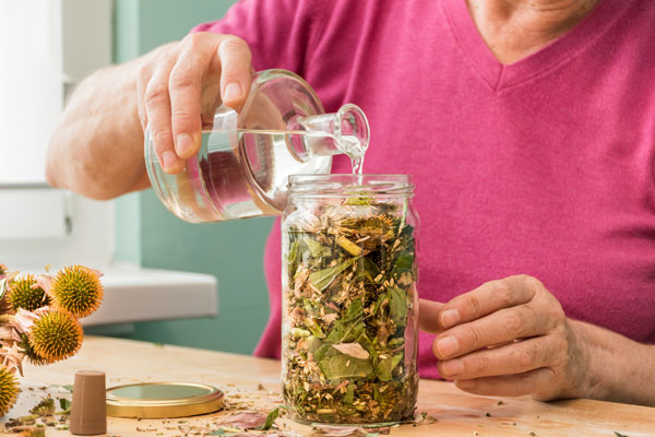 Pictured here is an at-home DIYer making an herbal
tincture in a mason jar. She is using food grade ethanol
190 proof for solvent extraction. This is a preparation
technique that uses ethanol to extract beneficial properties
from plants and herbs.